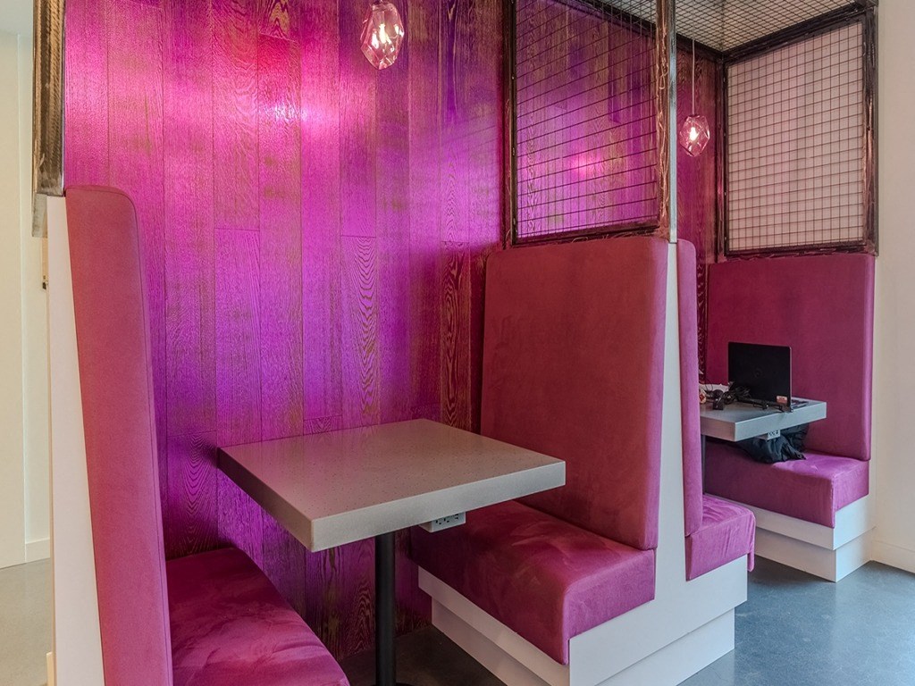 a room with two booths and a table and a pink wall